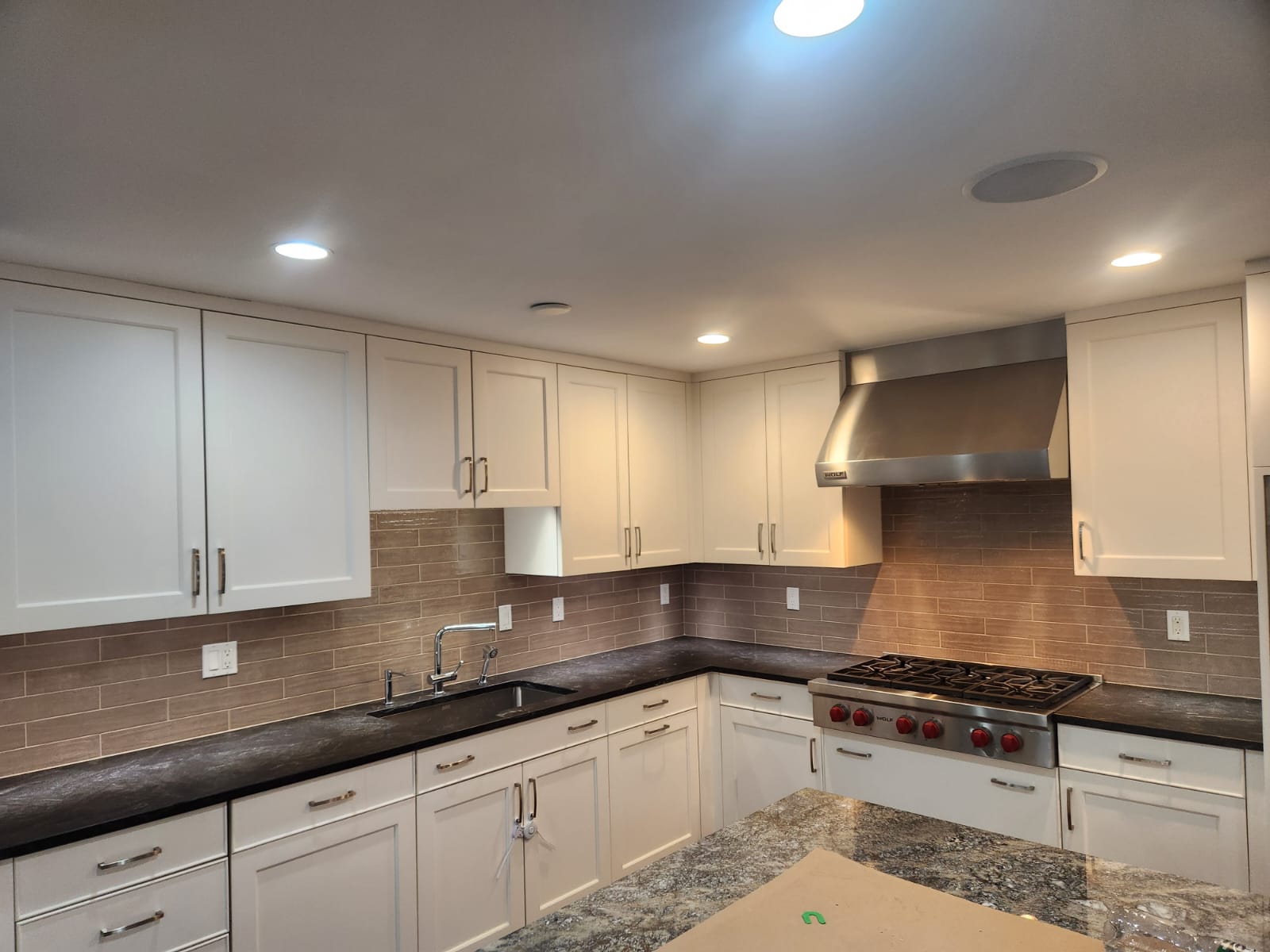 Staggered porcelain tile backsplash installation in Greenwich CT kitchen with granite countertops