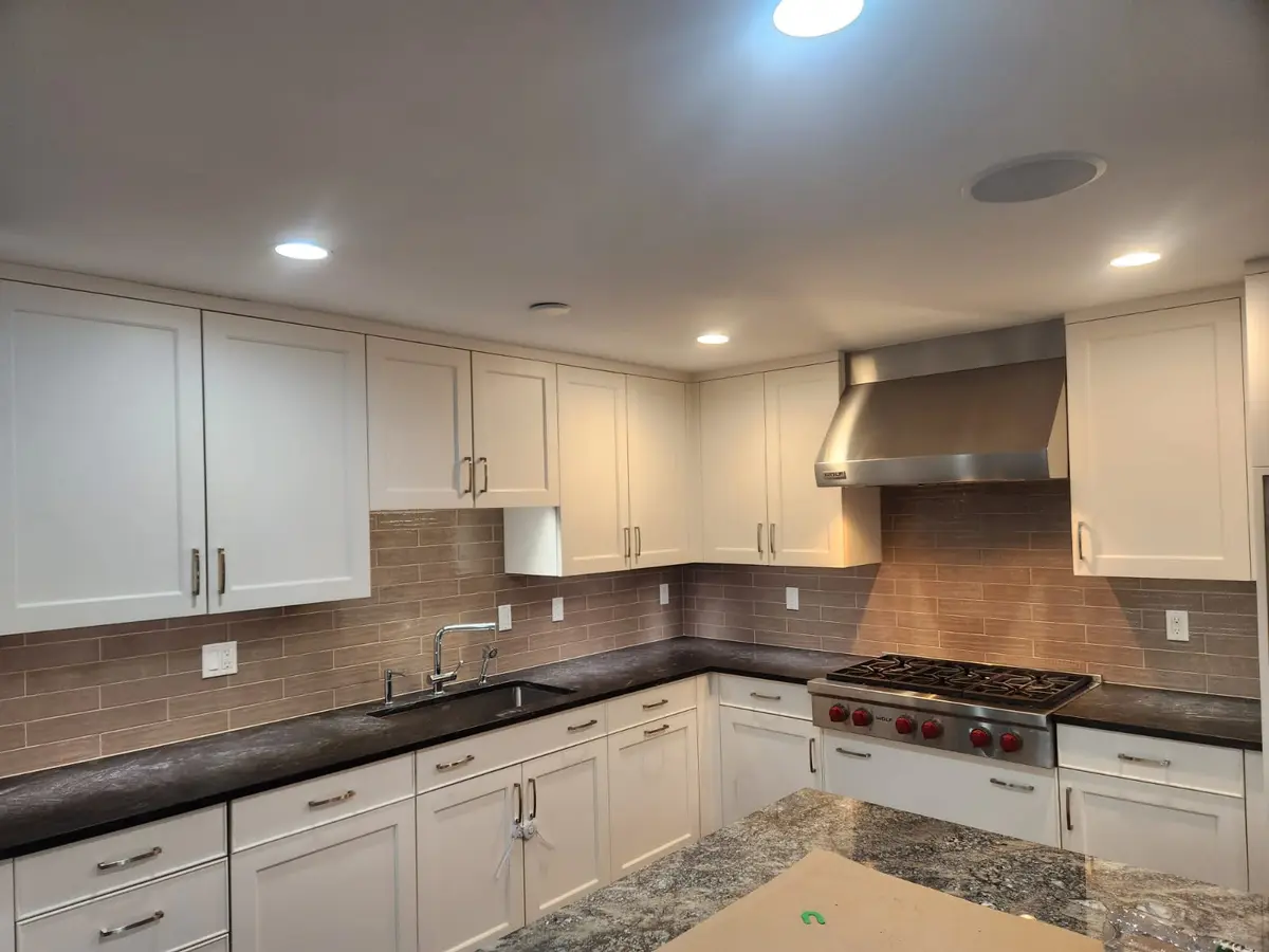 Staggered Porcelain Tile — Taupe staggered porcelain backsplash with a brushed finish, paired with white shaker cabinets and dark granite countertops